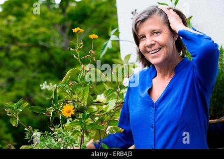 Portrait einer älteren Frau auf ihrem Balkon und lächelnd Stockfoto