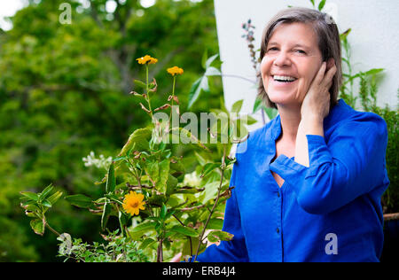 Portrait einer älteren Frau auf ihrem Balkon und lächelnd Stockfoto