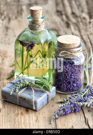 Lavendel ätherisches Öl, Kräuterseife und Badesalz mit frischen Blumen auf hölzernen Hintergrund Stockfoto