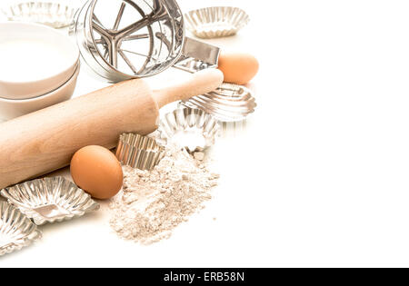 Backen, Zutaten und Maut für die Teigbereitung. Mehl, Eiern, Nudelholz und Ausstechformen auf weißem Hintergrund Stockfoto