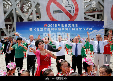 Peking, China. 31. Mai 2015. Man tanzt vor Anti-Raucher-Banner angezeigt auf des legendären Vogels Nest Nationalstadion während einer Veranstaltung Kennzeichnung Weltnichtrauchertag in Peking, Hauptstadt von China, 31. Mai 2015. Beijing plant neue Regelungen am 1. Juni, erfordern alle geschlossenen öffentlichen Orten- und viele Outdoor-öffentliche Orte - zu 100 % rauchfrei. Die Gesetzgebung gilt als das strengste Anti-Raucher-Gesetz in der Geschichte Chinas. © Shen Bohan/Xinhua/Alamy Live-Nachrichten Stockfoto