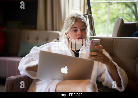 Ein blonder Teenager spielt mit ihren Laptop-Computer und iphone Stockfoto