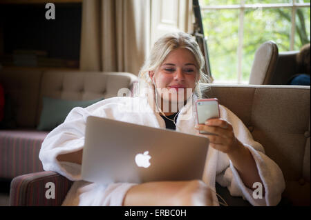 Ein blonder Teenager spielt mit ihren Laptop-Computer und iphone Stockfoto