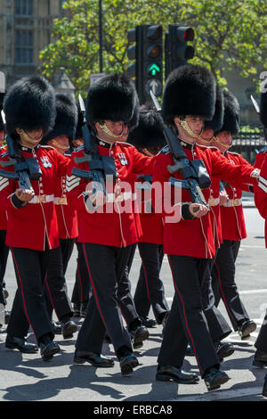 Soldaten aus der Grenadier Guards in feierlichen roten Uniformen, marschieren von der Parlamentseröffnung an einem sonnigen Tag Stockfoto