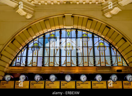 Gewölbte Innenraum des Flinders Street Station mit viktorianischen Glasfenster mit den berühmten Uhren zeigen Fahrplan Stockfoto