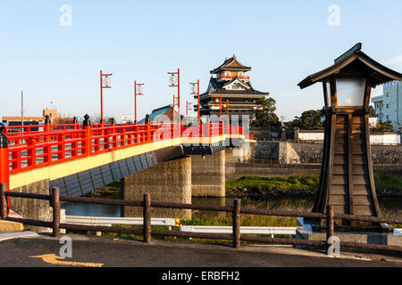 Japan, Nagoya. Betonrekonstruktion der Holzbrücke mit Melionengeländern und Lampen, die zur Burg Kiyosu mit blauem Himmelshintergrund führt. Stockfoto