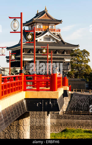 Japan, Nagoya. Betonrekonstruktion der Holzbrücke mit Melionengeländern und Lampen, die zur Burg Kiyosu mit blauem Himmelshintergrund führt. Stockfoto