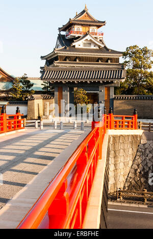 Japan, Nagoya. Betonrekonstruktion der Holzbrücke mit Melionengeländern und Lampen, die zur Burg Kiyosu mit blauem Himmelshintergrund führt. Stockfoto