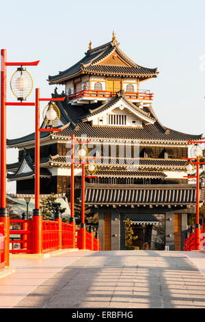 Japan, Nagoya. Betonrekonstruktion der Holzbrücke mit Melionengeländern und Lampen, die zur Burg Kiyosu mit blauem Himmelshintergrund führt. Stockfoto