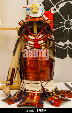 Roter Anzug aus Samurai-Rüstung mit einem Kabuto-Helm und einem schwarzen Banner im Inneren des Bergungsaufzugs auf der Burg Kiyosu in Nagoya, Japan. Stockfoto