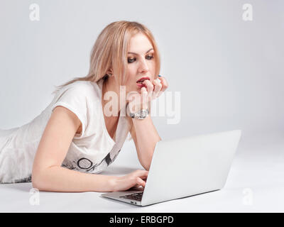 Junge Frau mit Laptop auf dem Boden liegend Stockfoto
