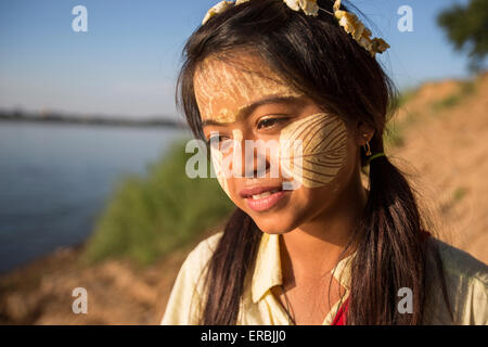 Hübsches junges Mädchen mit Blattgold auf Gesicht am Ufer des Ayeyarwady Fluss, Myanmar Stockfoto