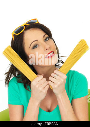 Attraktive junge Frau mit Handvoll bereit zu Kochen getrocknete Italienische Spaghetti Pasta Isoliert gegen einen weißen Hintergrund mit Kopie Raum Stockfoto