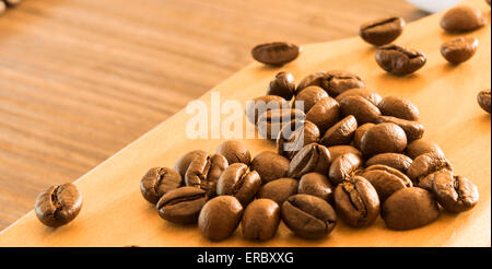 Kaffeebohnen in Form von Herzen auf Holzbrett angeordnet Stockfoto