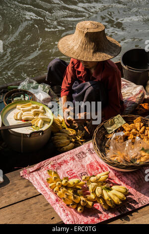 Eine Frau verkauft Lebensmittel aus ihrem Boot, Damnern Saduak Floating Market, Bangkok, Thailand. Stockfoto