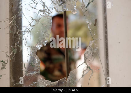 Eine kurdische Peshmerga Soldat ist durch ein Fenster eines Hauses, das mit einschusslöchern nach einer Schlacht mit ISIS oder ISIL-Aktivisten in der Stadt Makhmur in der Nähe von Mosul im Irak enträtselt gesehen Stockfoto