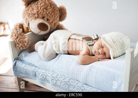 Neugeborene schlafen mit einem Teddybär Stockfoto