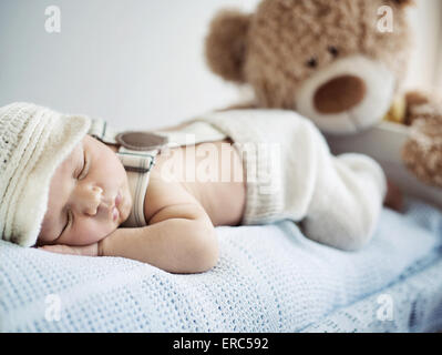 Neugeborene schlafen mit einem Teddybär Stockfoto