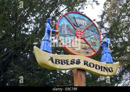 Geschnitzte hölzerne Ortsschild zeigt zwei Äbtissinnen in blauen Gewändern, Äbtissin Roding (oder des Abtes Roding), Essex, England Stockfoto