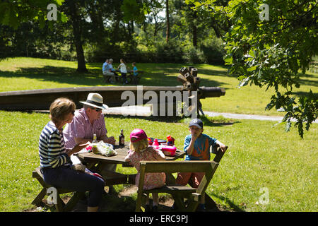 Styal, Steinbruch-Bank-Mühle, Kinder Picknick in der Sonne mit Großeltern am alten Wasserrad hub Stockfoto