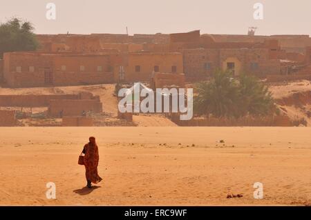 Frau in einem trockenen Flussbett, Wadi oder Oued, vor dem historischen Zentrum, Chinguetti, Adrar Region, Mauretanien Stockfoto
