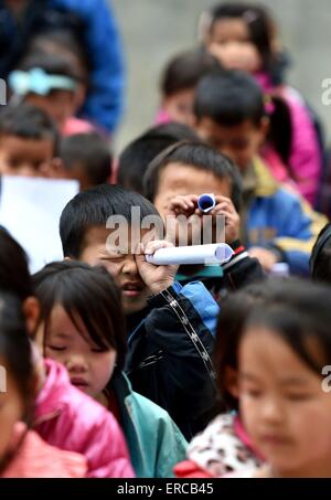 (150601)--DAHUA, 1. Juni 2015 (Xinhua)--SchülerInnen suchen durch Papier Teleskope in Nongyong Elementary School in dann Township von Yao Dahua autonome Grafschaft, 7. März 2015. Juni 1 markiert den Internationalen Kindertag. (Xinhua/Huang Xiaobang) (Lfj) Stockfoto