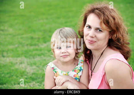 Outdoor Sommer Portrait einer echten kaukasischen Familie, junge Mutter mit ihrer kleinen süßen Tochter Stockfoto