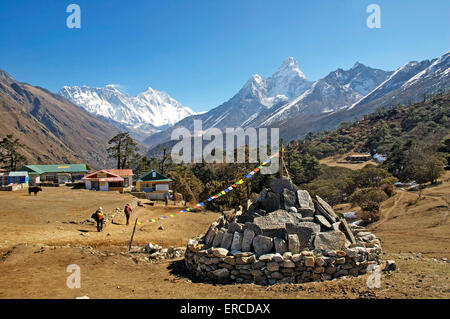 Mani-Steinen und Gebetsfahnen im Zentrum von Tengboche, Nepal.  Die Doppelspitzen der Ama Dablam dominieren die Skyline. Stockfoto