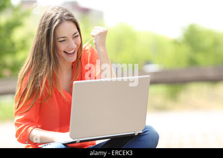 Euphorische Frau Job mit einem Laptop in einem städtischen Park im Sommer-Suche Stockfoto