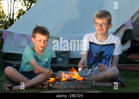 Kinder Rösten Marshmallows über ein Lager Feuer während Glamping camping im Vereinigten Königreich Stockfoto