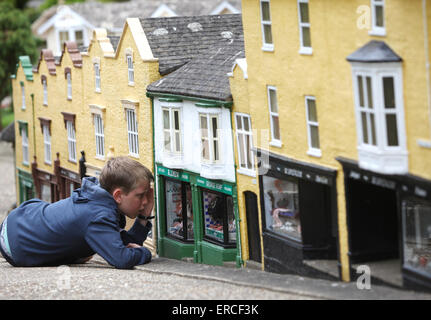 Ein Junge sieht aus wie ein Riese, wie er bei einem Besuch in The Model Village in Godshill auf der Isle Of Wight durch ein Schaufenster aussieht Stockfoto