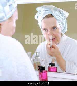 Applying Reife Frau tun Make up im Schlafzimmer Spiegel am Schminktisch Stockfoto