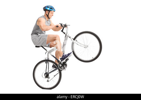 Studioaufnahme der fröhliche junge Biker tun einen Wheelie mit seinem Fahrrad isoliert auf weißem Hintergrund Stockfoto