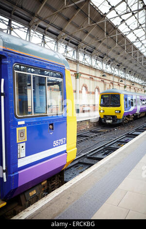 Manchester Piccadilly (links) ein Norther Rail Klasse 142 Pacer in lila Livree des Unternehmens und eine Klasse 323 Ankunft Eisenbahnen Stockfoto