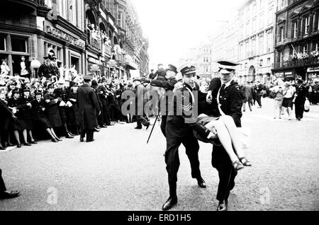 Die Beatles in Liverpool, 10. Juli 1964. Liverpool-Filmpremiere von "A Hard Day Night" im Odeon-Kino. St Johns Ambulance Personal entführen ein junges Mädchen zu überwinden. Stockfoto