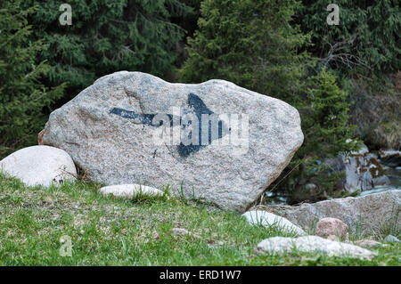 Schwarzer Pfeil auf den Stein gemalt auf einem Felsen im Wald Stockfoto