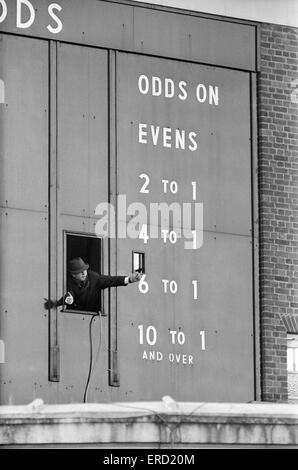 Hinter den Kulissen im Sandown Park vor einem zweitägigen treffen. Das riesige Totebrett, das die Quoten bei Hausmeister geben den Daumen nach oben Zeichen aus dem Fenster registriert. 28. Dezember 1967. Stockfoto