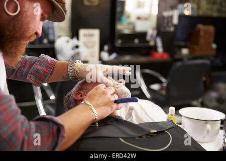 Barbier rasieren Client mit Kehle Rasiermesser Stockfoto