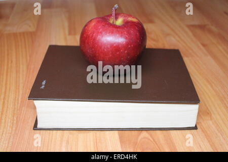 appetitlicher roter großen Apfel lag auf dickes Buch in braun Abdeckung Stockfoto