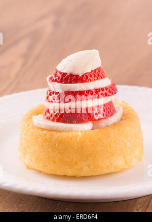 Dessert-Schale mit in Scheiben geschnittenen Erdbeeren und Bananen, auf einem weißen Teller Stockfoto