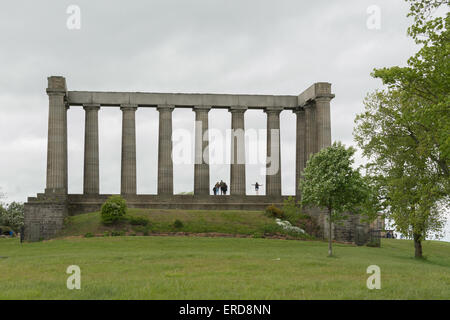 Touristen posieren für Fotos in der unvollendeten National Monument of Scotland auf Calton Hill an einem windigen grauen Tag in Edinburgh Stockfoto