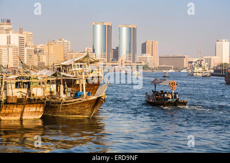 Traditionellen, alten arabischen Dhaus vertäut am Kai in Deira, Dubai Creek, Vereinigte Arabische Emirate, mit modernen Wolkenkratzern und Fähre Stockfoto