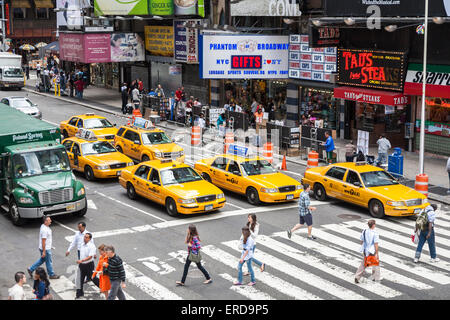 NYC Sightseeing: legendäre New York City gelbe Taxis auf einen Zebrastreifen auf dem Times Square in Manhattan, warten als Fußgänger die Straße überqueren Stockfoto