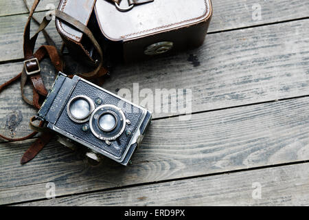 Alten Retro-Kamera und Gürtel Tasche (Ledertasche) auf Vintage Holzbretter abstrakten Hintergrund Stockfoto