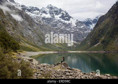 Zwei Wanderer den Blick auf Lake Marian in den Darran Bergen von Fjordland in Südinsel Neuseeland Stockfoto