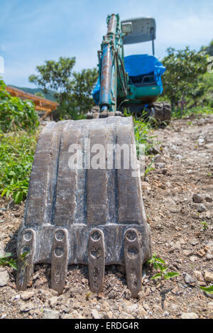 Eine Weitwinkeleinstellung eines schmutzigen Baggers in Schmutz und Felsen sitzen. Stockfoto