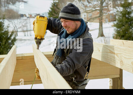 Kaukasische Zimmermann mit Bohrmaschine im winter Stockfoto