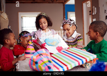Kinder tragen Diademe und Geschenke öffnen Stockfoto