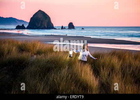 Kaukasische Frau, die die Laterne auf Cannon Beach, Oregon, Vereinigte Staaten Stockfoto