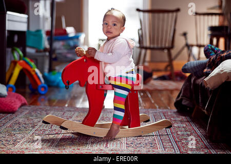 Gemischte Rassen Babymädchen spielen auf Schaukelpferd Stockfoto